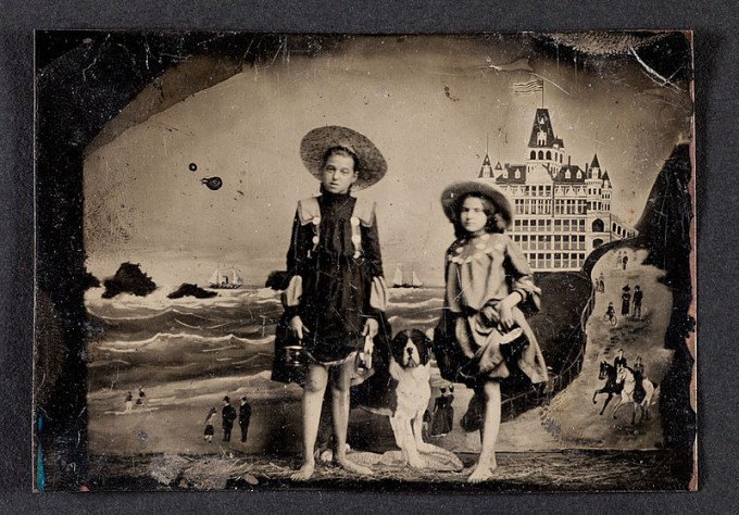 Tintype of two girls in front of a painted background of the Cliff House and Seal Rocks in San Francisco, ca. 1900